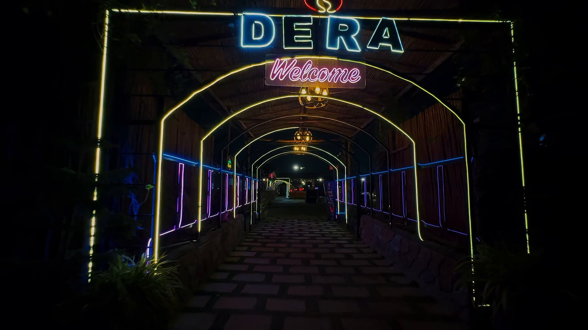 The neon DERA welcome arch over the walkway into the restaurant at night