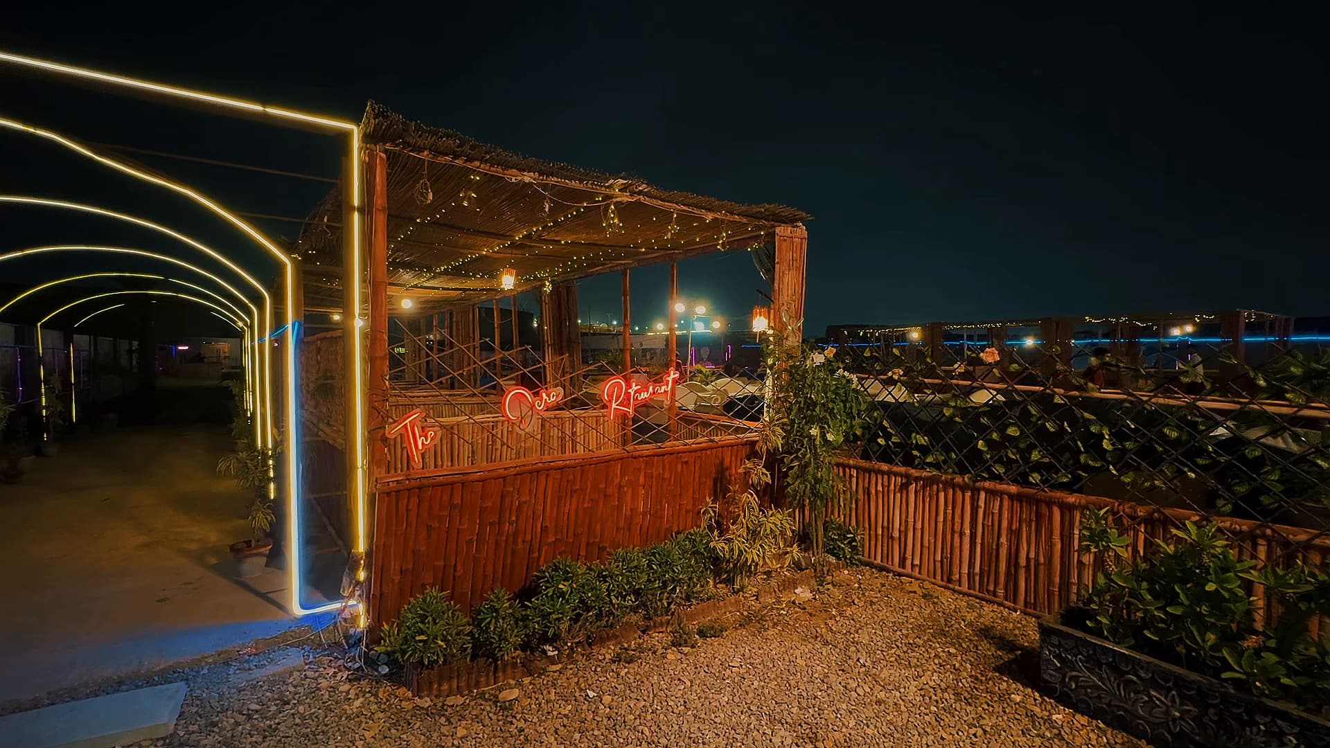 Bamboo hut seating framed by glowing neon arches